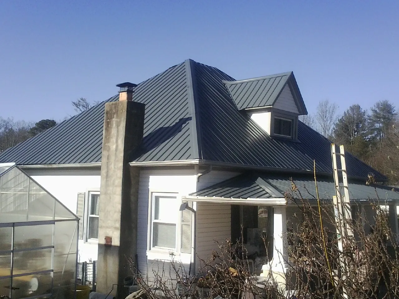 Dark blue standing seam metal roof on a white farmhouse with dormer — Slate & Tile Roof Repair by Roofing Brothers in Marion