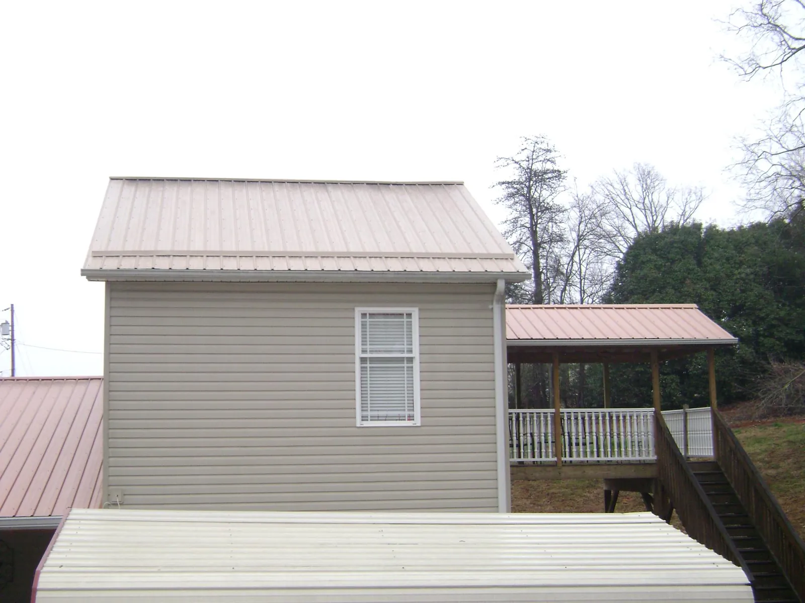 Tan metal roofs on a two story addition and attached porch, from a Roof Replacement job in Marion